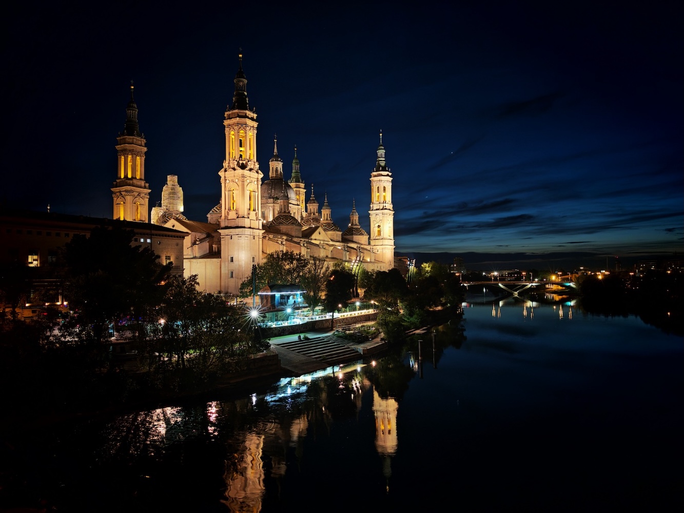 Basílica del Pilar iluminada de noche reflejada en el río Ebro